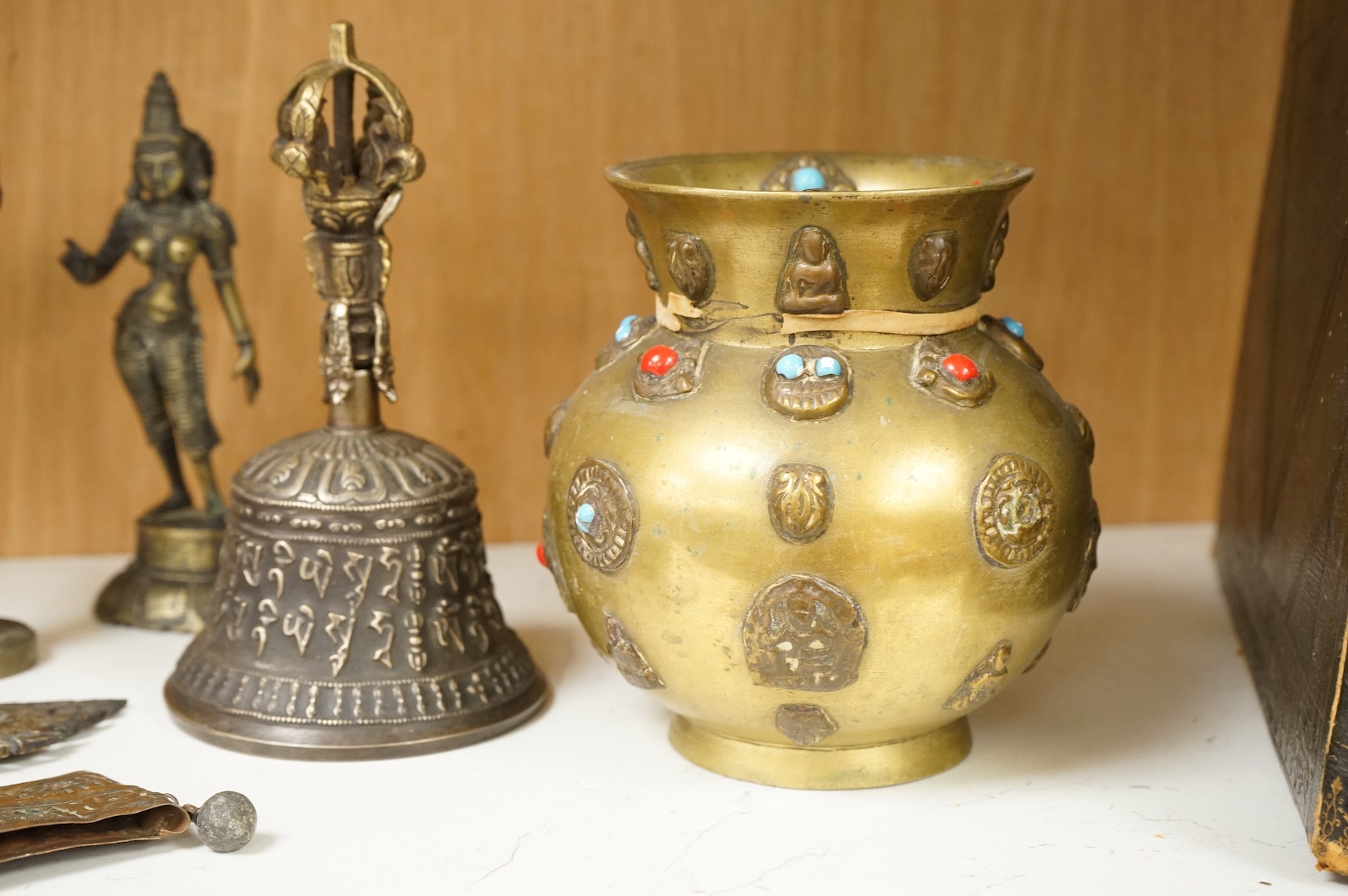 A group of Tibetan brass and mixed metal artefacts to include a brass vase with cabochon inset stones and figures of deities, largest 22cm high